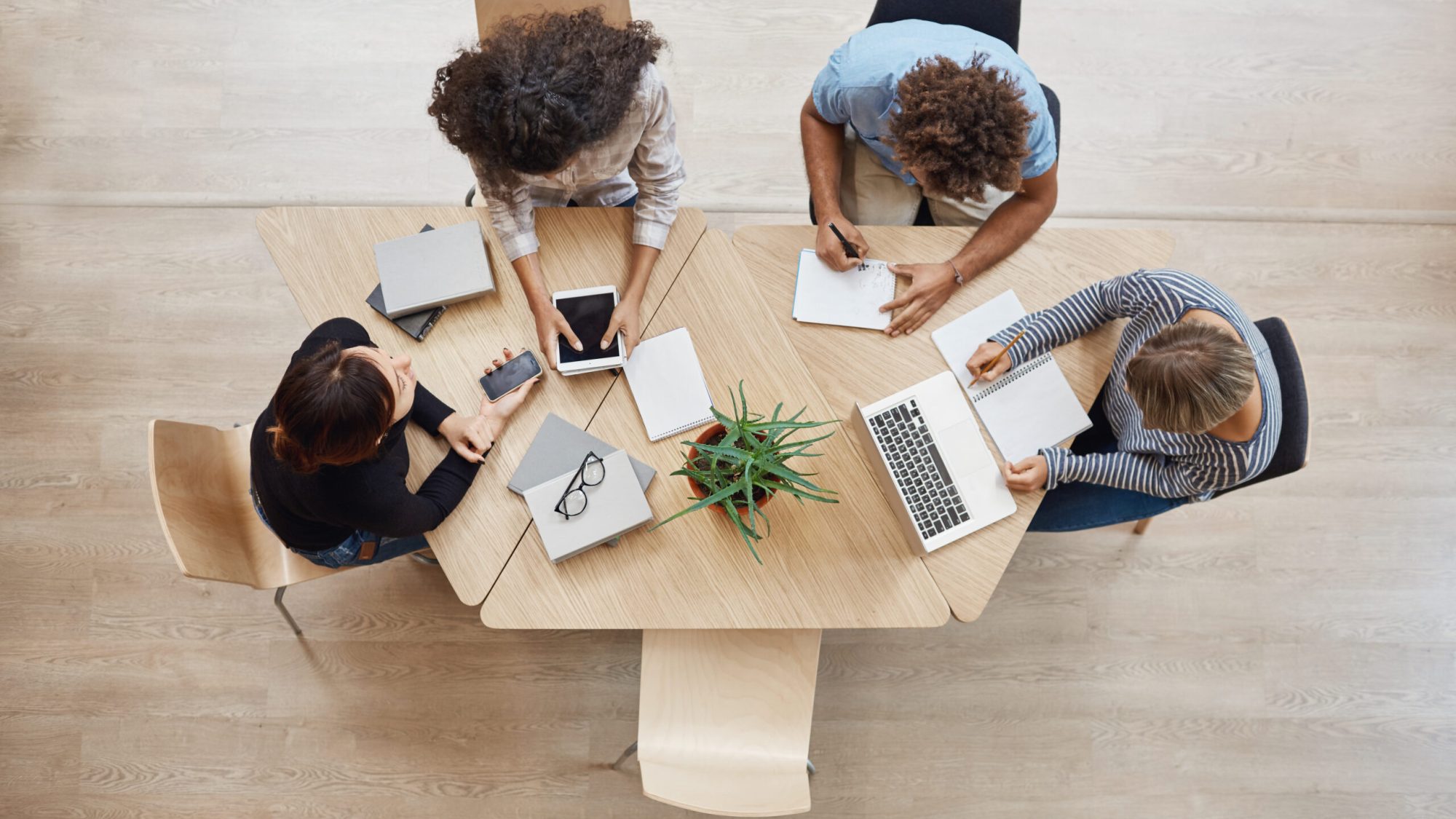 View from above. Business,startup, teamwork concept. Startup partners sitting at coworking space talking about future project, looking through examples of work on laptop and digital tablet